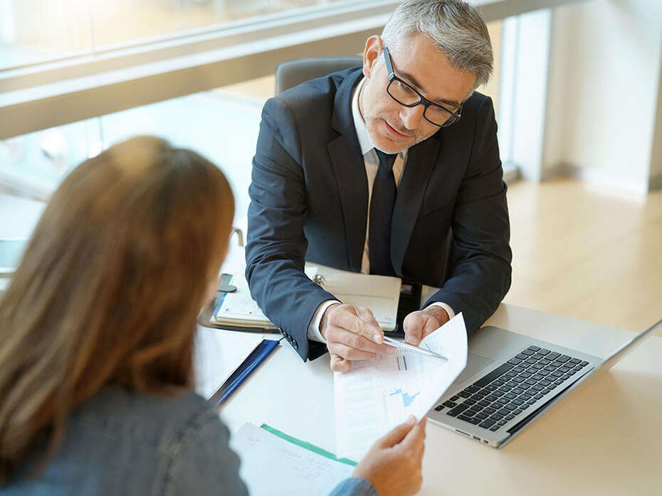 Ekspert tłumaczy klientce jak budować pozytywną historię kredytową. Na biurku widoczny laptop.